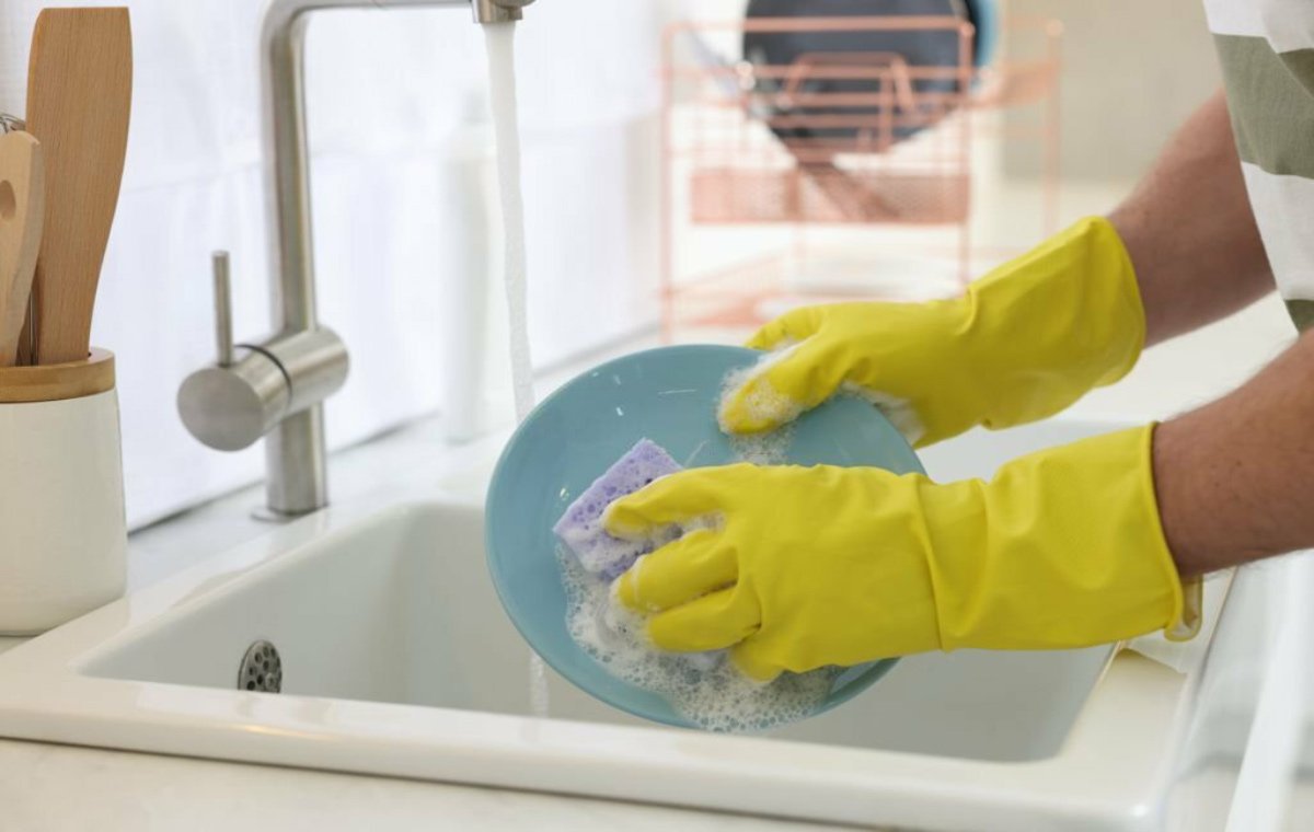 فردی که دستکش پوشیده است و ظرف می‌شوید