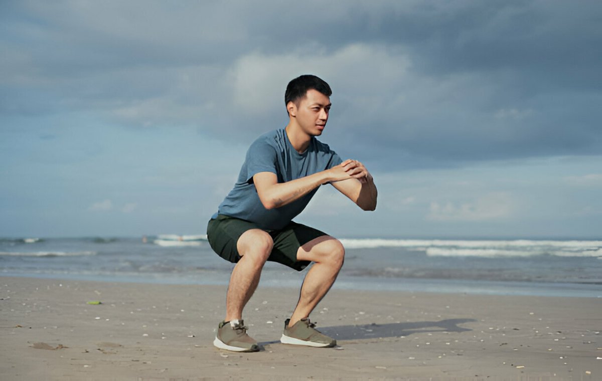 یک مرد جوان که در ساحل حرکت اسکات را برای غلبه بر علت لاغری پاها انجام می‌دهد