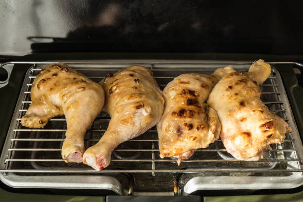 Chicken leg cooking on electric grill with broccoli gratin plate