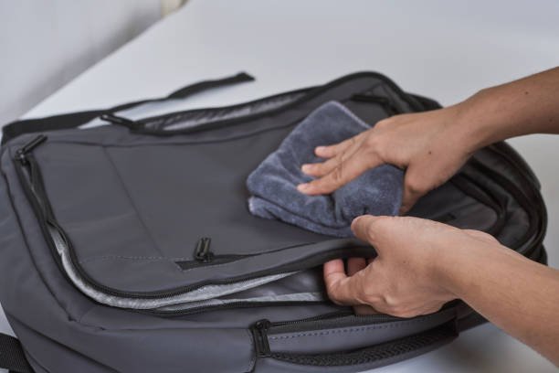 Cleaning backpack with washcloth. A person wipes off dirt or dust from the outside of the bag. Wiping school bag with damp cloth