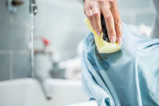 Woman Cleaning Stained Clothing With Cleaning Sponge.