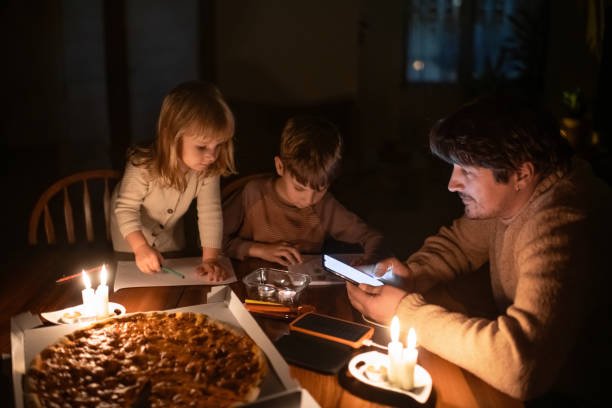 Family sitting at home with candles during blackout.